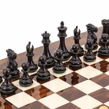 Schwarze Schachfiguren aus Ebenholz aufgereiht auf dem Wurzelholz-Schachbrett