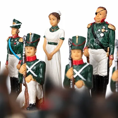 Schachfiguren mit Soldaten in grüner Uniform und Dame im weißen Kleid
