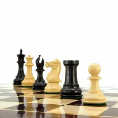 Schachfiguren aus Buchsbaum und Ebenholz perspektivisch auf dem Brett aufgereiht