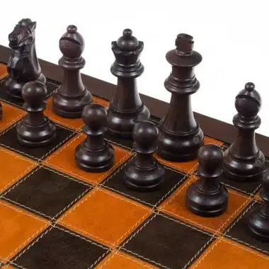 Rosenholzfiguren aufgestellt auf einem Schachbrett aus orangefarbenem und braunem Leder