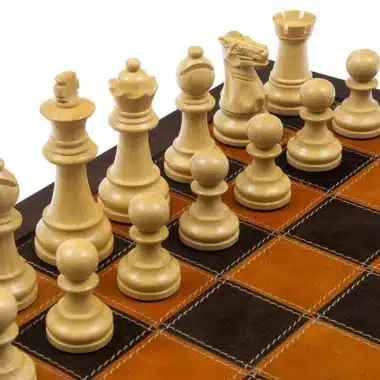 Schachfiguren aus hellem Buchsbaum auf einem zweifarbigen Lederschachbrett
