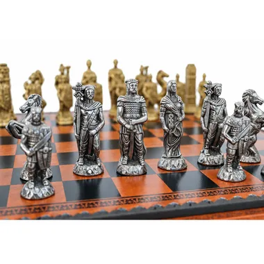 Gold- und silberfarbene Metallfiguren aufgereiht auf dem Kunstleder-Schachbrett