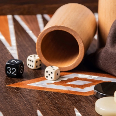 Holzwürfelbecher mit klassischen Würfeln und Verdopplungswürfel auf dem Spielbrett