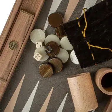 Spielsteine, Würfel und Samtbeutel auf dem Backgammon-Spielfeld